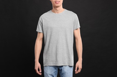 Photo of Man wearing light gray t-shirt on black background, closeup. Mockup for design