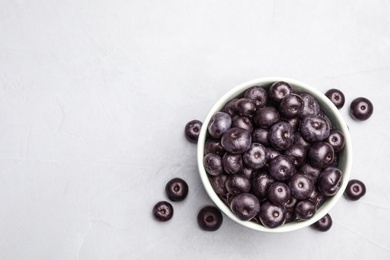 Photo of Bowl of fresh acai berries on light stone table, flat lay. Space for text