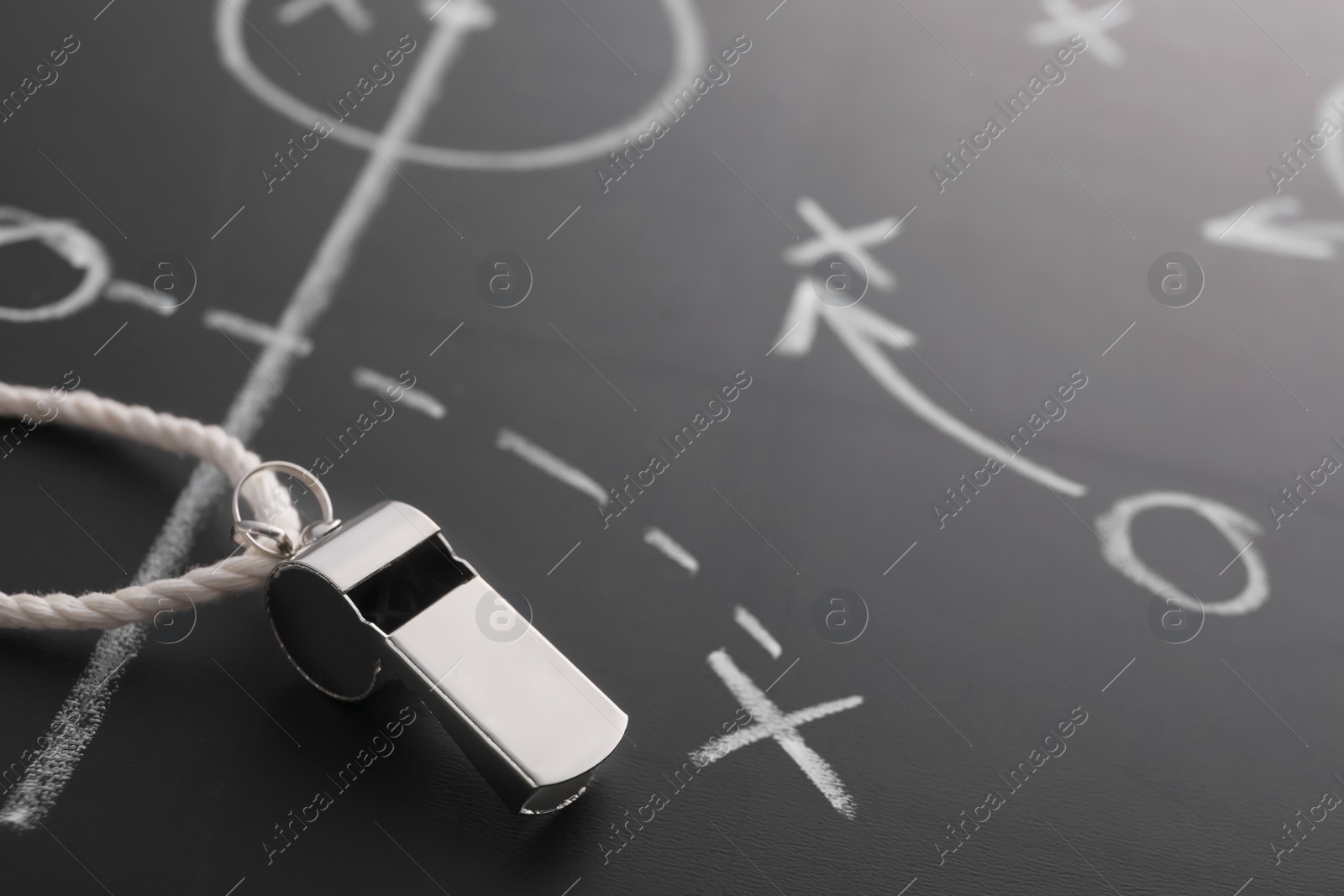 Photo of Referee whistle on chalkboard with game scheme, closeup