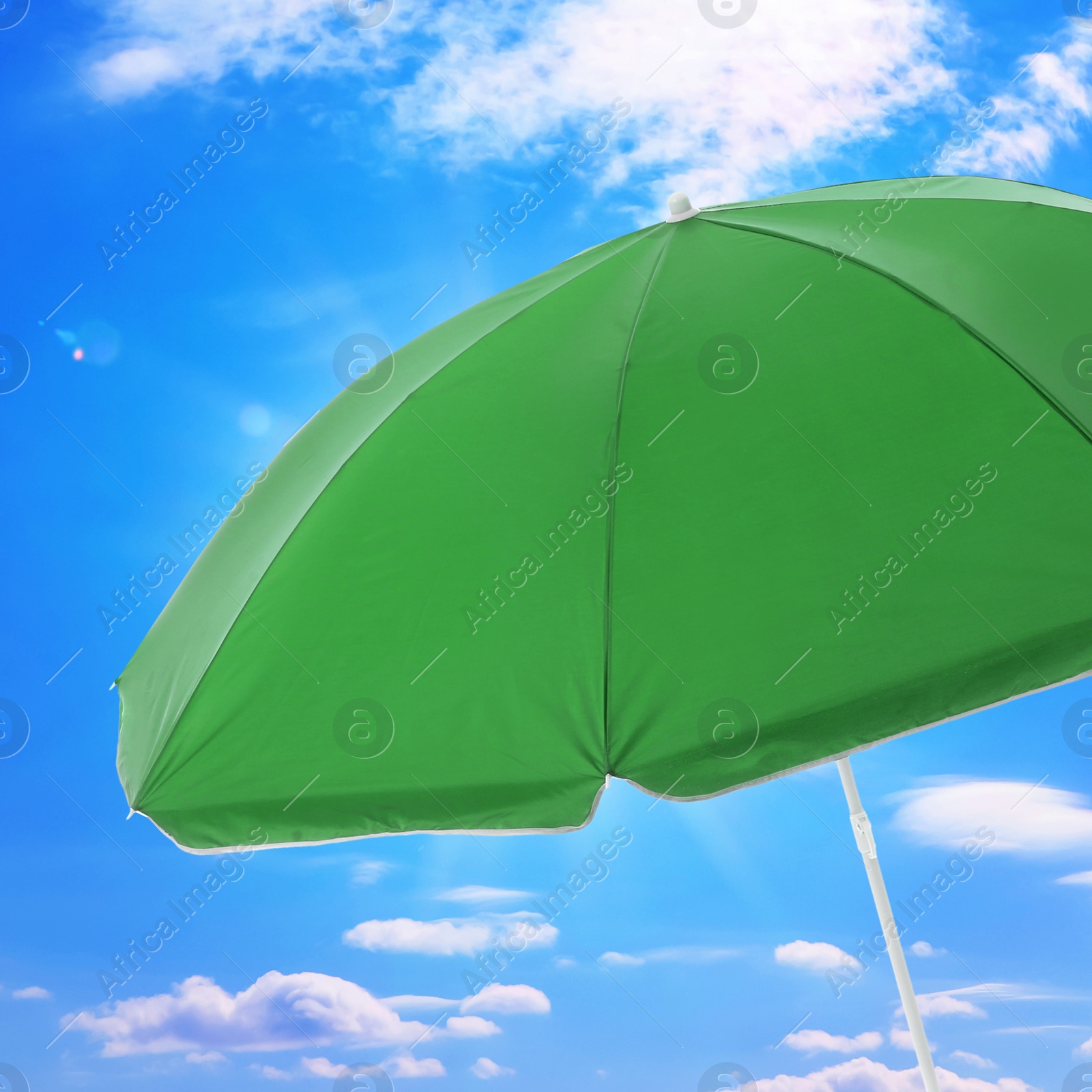 Image of Open big green beach umbrella and beautiful blue sky with white clouds on background