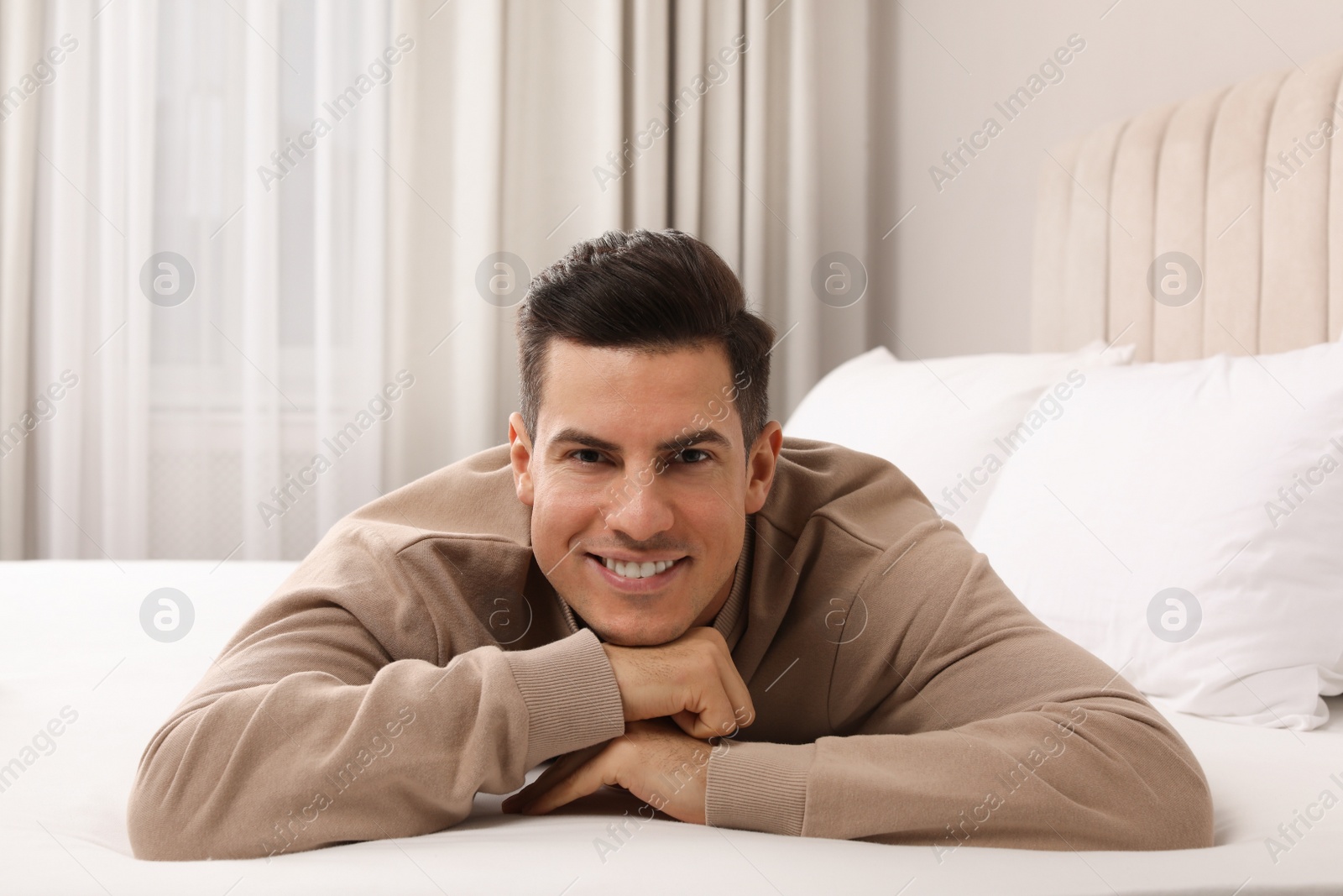 Photo of Happy man lying on bed at home