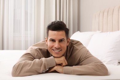 Happy man lying on bed at home
