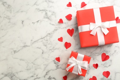 Photo of Beautiful gift boxes and paper hearts on marble table, flat lay with space for text. Valentine's Day celebration