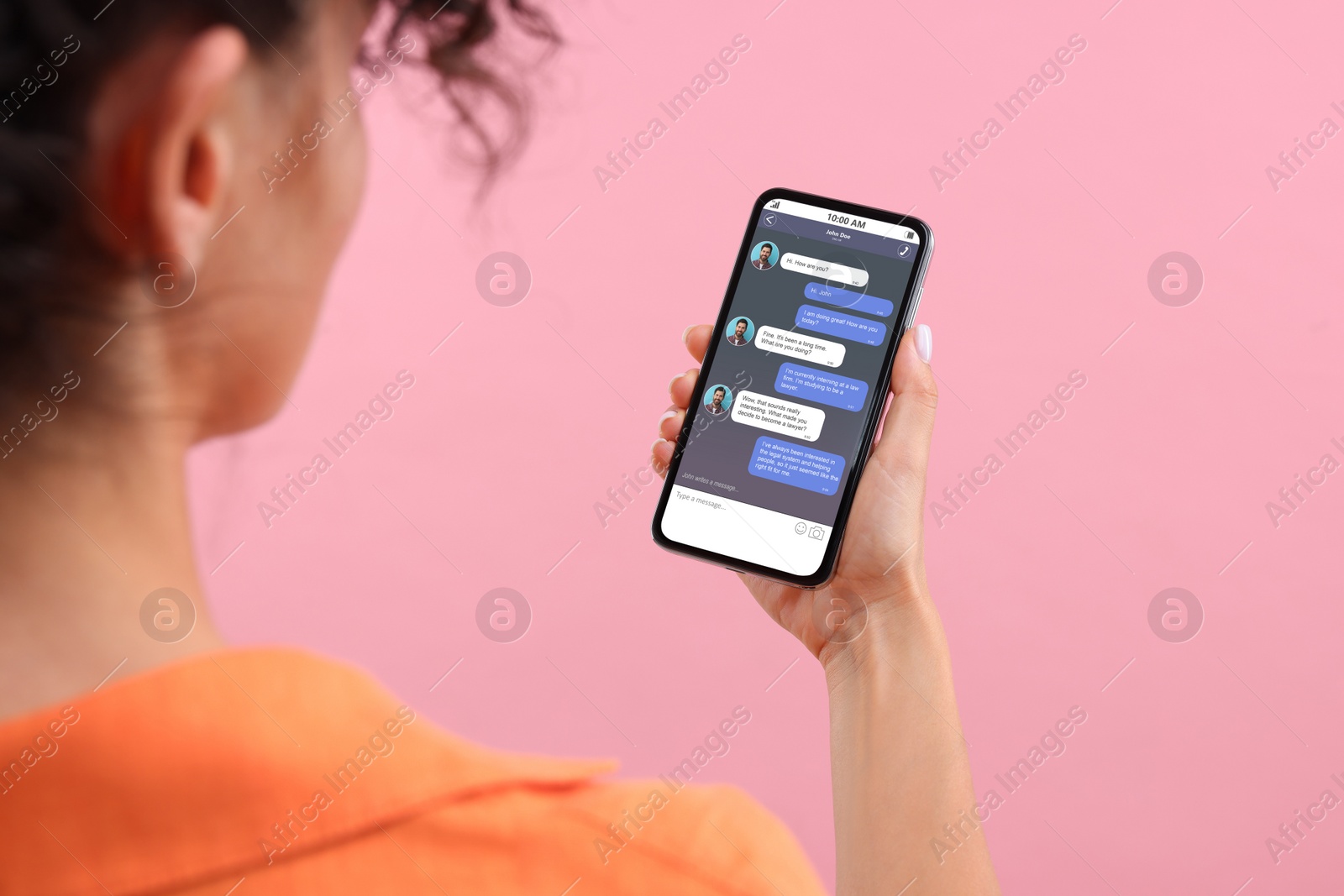 Image of Woman texting with friend using messaging application on smartphone against pink background, closeup