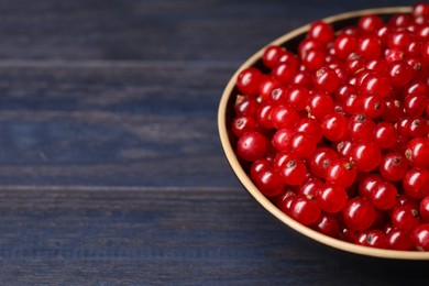 Photo of Ripe red currants in bowl on wooden rustic table, closeup. Space for text