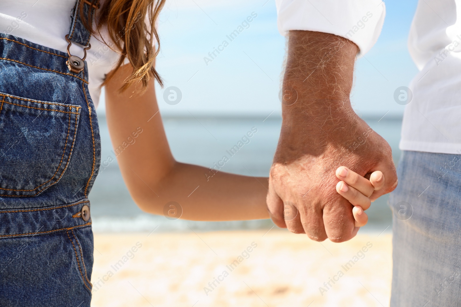 Photo of Little girl with grandfather on sea beach, closeup