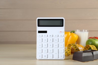 Photo of Calculator and food products on wooden table, space for text. Weight loss concept