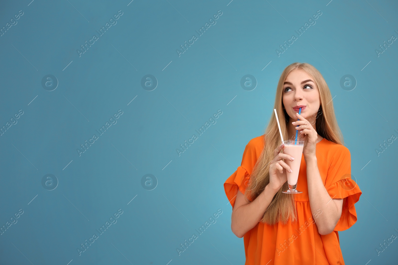 Photo of Young woman with glass of delicious milk shake on color background