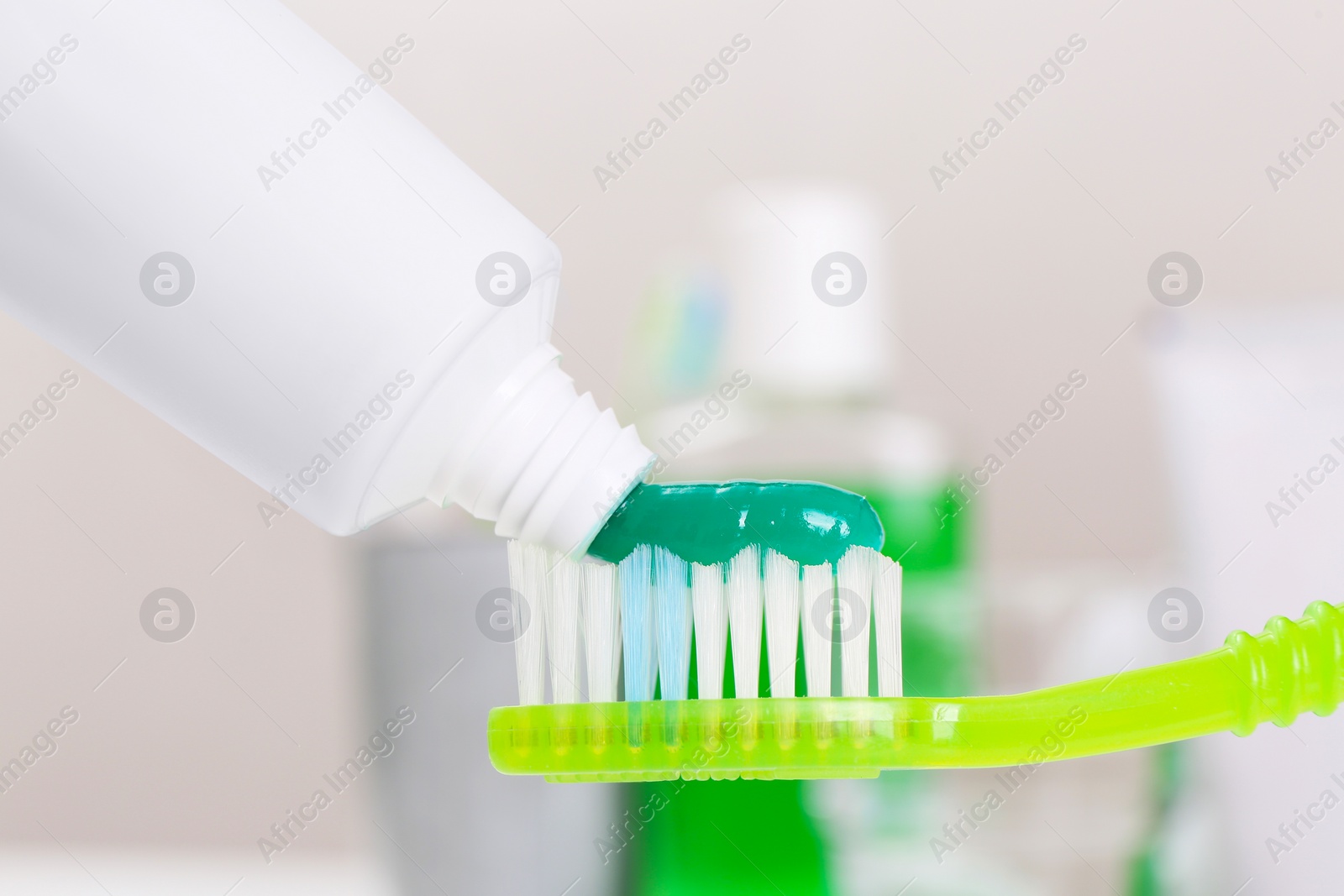 Photo of Applying paste on toothbrush near mouthwash, closeup