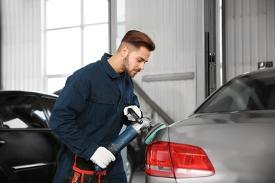 Photo of Technician polishing car body with tool at automobile repair shop