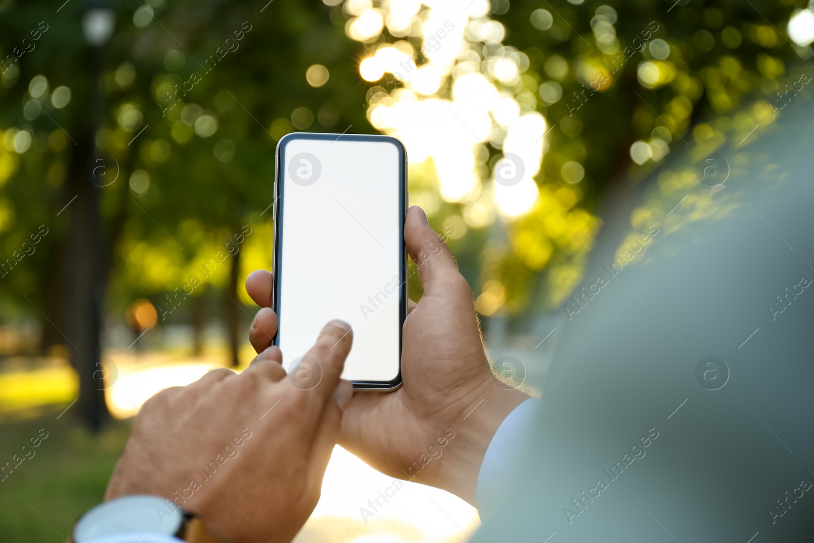 Photo of Man using modern mobile phone in park, closeup