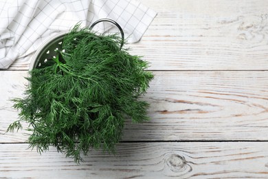 Photo of Fresh dill in colander on white wooden table, top view. Space for text