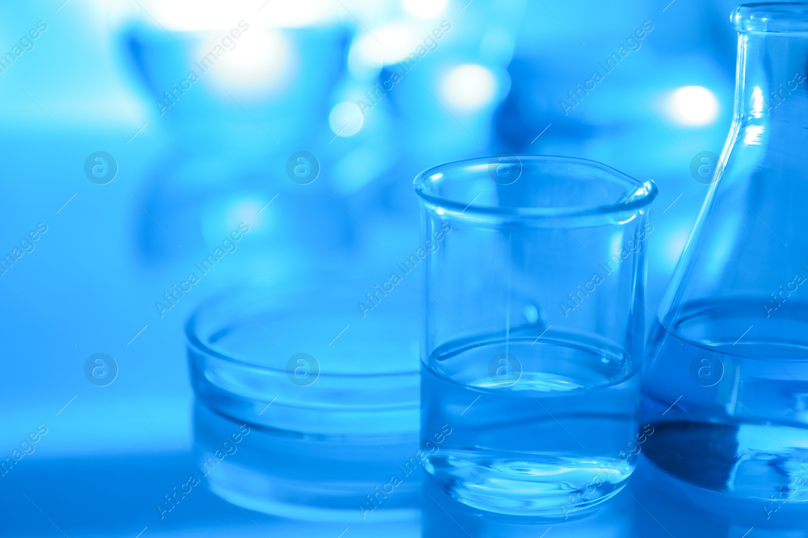 Photo of Laboratory glassware with liquid on table. Space for text