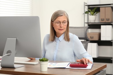 Photo of Senior accountant working at wooden desk in office