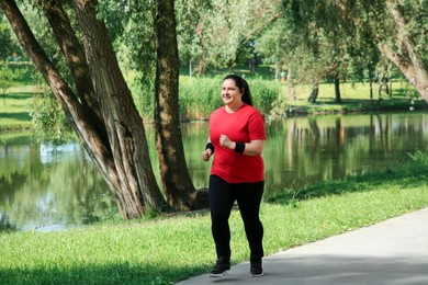 Photo of Overweight woman jogging near pond in park