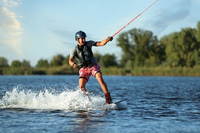 Photo of Teenage boy wakeboarding on river. Extreme water sport