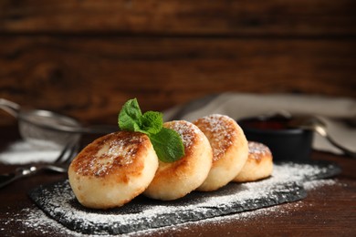 Photo of Delicious cottage cheese pancakes with mint and icing sugar on wooden table