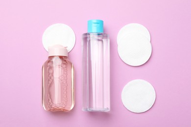 Photo of Flat lay composition with bottles of micellar water and cotton pads on pink background