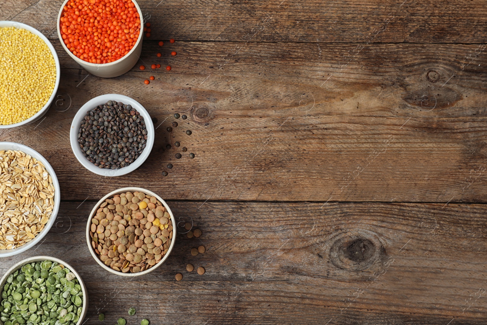 Photo of Flat lay composition with different types of legumes and cereals on wooden table, space for text. Organic grains