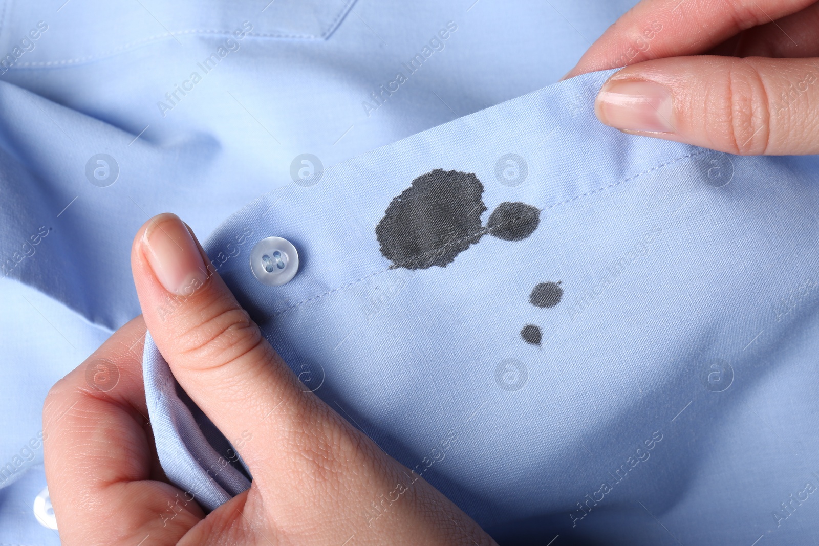 Photo of Woman holding shirt with black ink stain, closeup