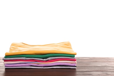 Pile of ironed clothes on table against white background. Space for text