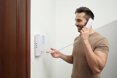 Man with handset answering intercom call indoors