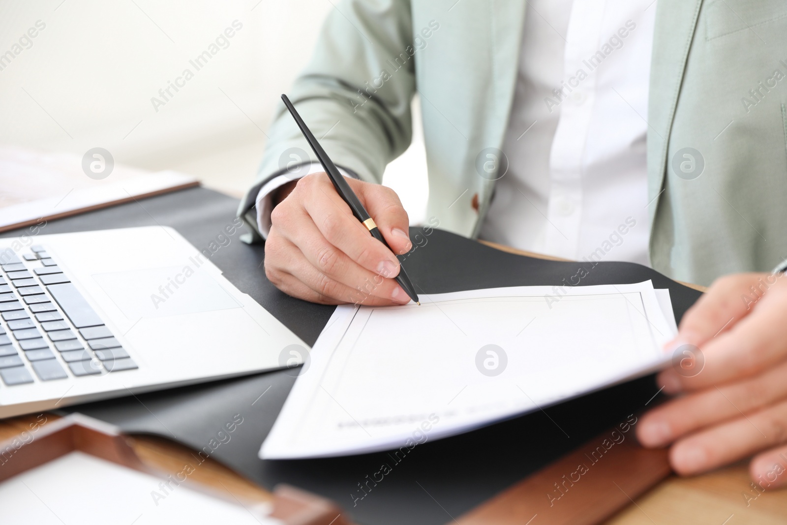 Photo of Male notary signing document at table in office, closeup