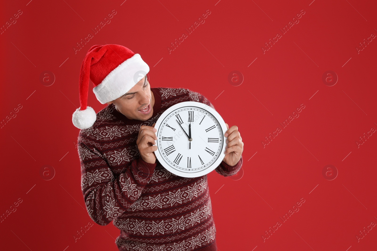 Photo of Man in Santa hat with clock on red background. New Year countdown