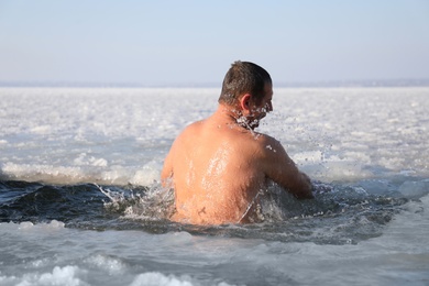 Photo of MYKOLAIV, UKRAINE - JANUARY 06, 2021: Man immersing in icy water on winter day, back view