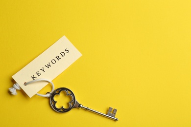 Vintage key and tag wIth word KEYWORDS on yellow background, top view. Space for text