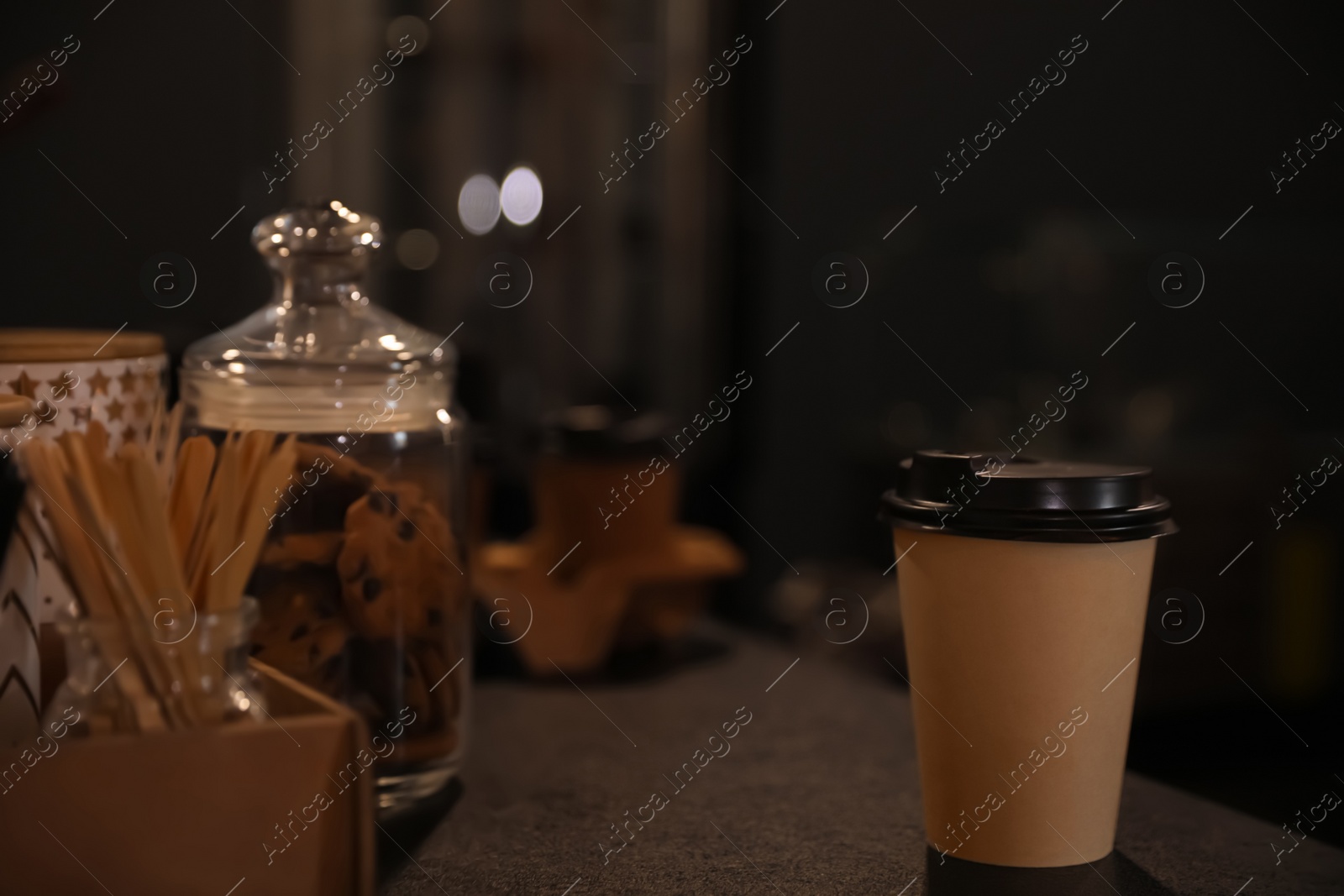 Photo of Takeaway coffee cup with plastic lid on grey table in cafe