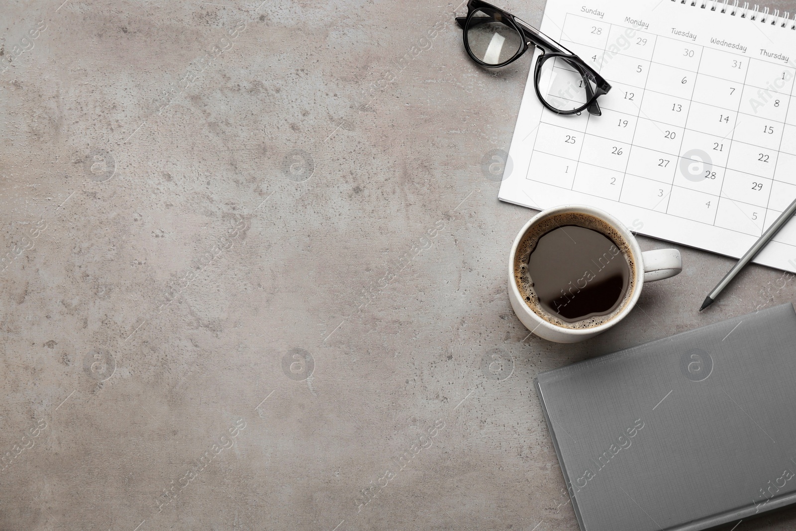 Photo of Flat lay composition with calendar and cup of coffee on grey stone table. Space for text