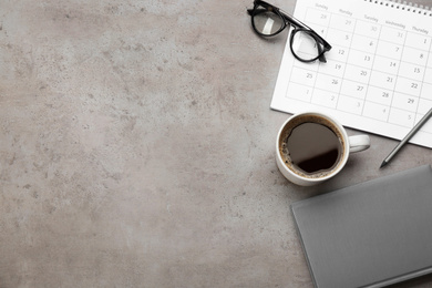 Flat lay composition with calendar and cup of coffee on grey stone table. Space for text