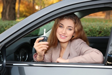 Photo of Happy woman holding car key in auto. Driving license test