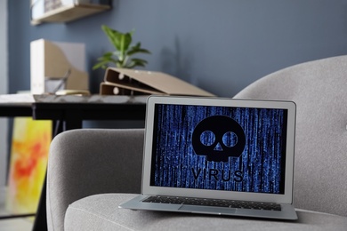 Photo of Laptop with virus illustration on grey sofa indoors