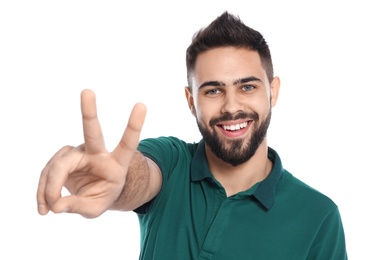 Photo of Happy young man showing victory gesture on white background