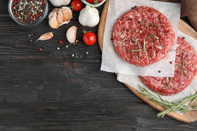 Photo of Flat lay composition with raw meat cutlets for burger on black wooden table. Space for text