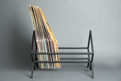 Rack with vinyl records in sleeves on grey background