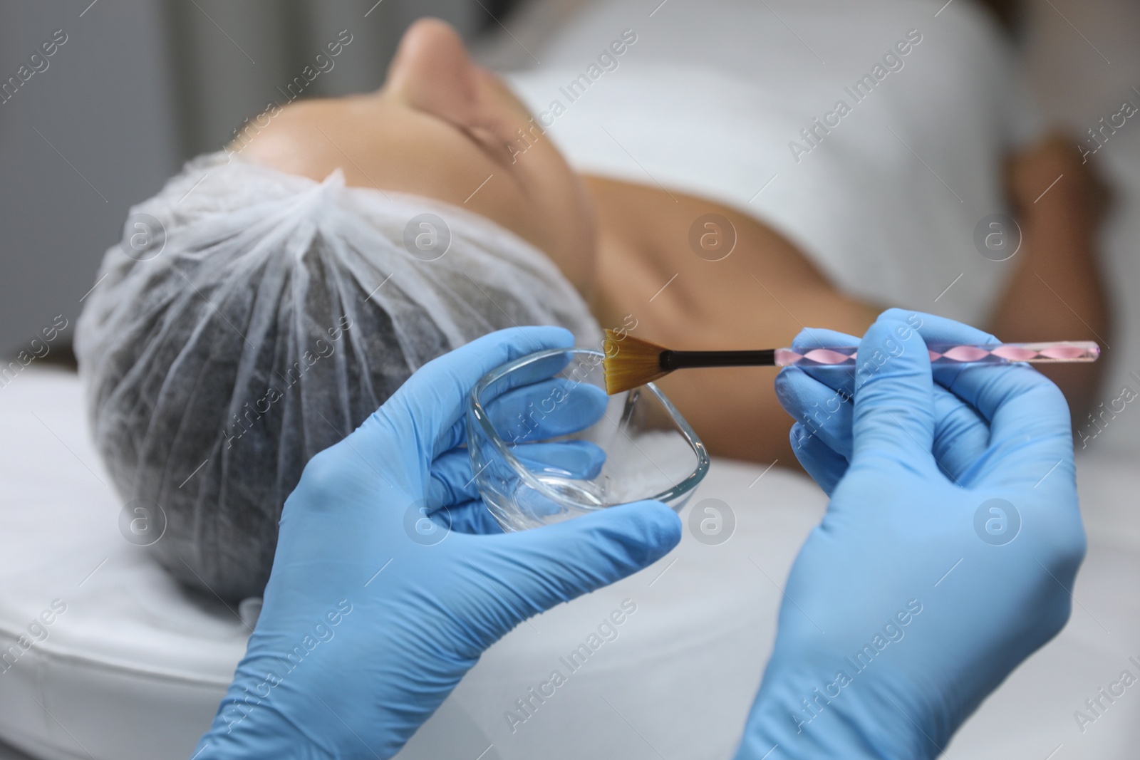 Photo of Cosmetologist with bowl and brush in salon. Peeling procedure