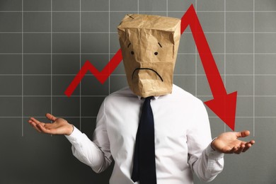 Image of Man wearing paper bag with drawn sad face and illustration of falling down chart on light grey background. Economy recession concept