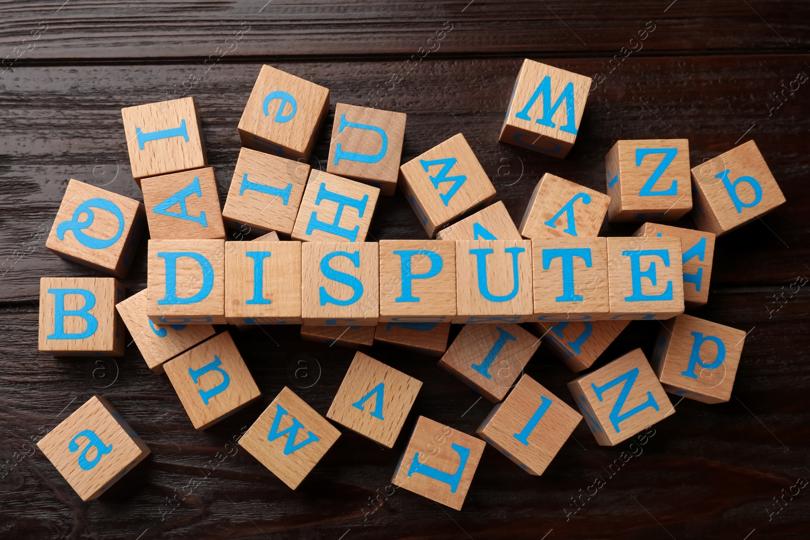 Photo of Cubes with word Dispute on dark wooden table, flat lay