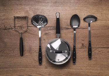 Photo of Set of cooking utensils on wooden table, flat lay
