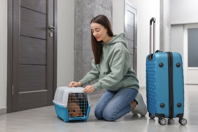 Photo of Travelling with pet. Woman looking at carrier with her dog in hall