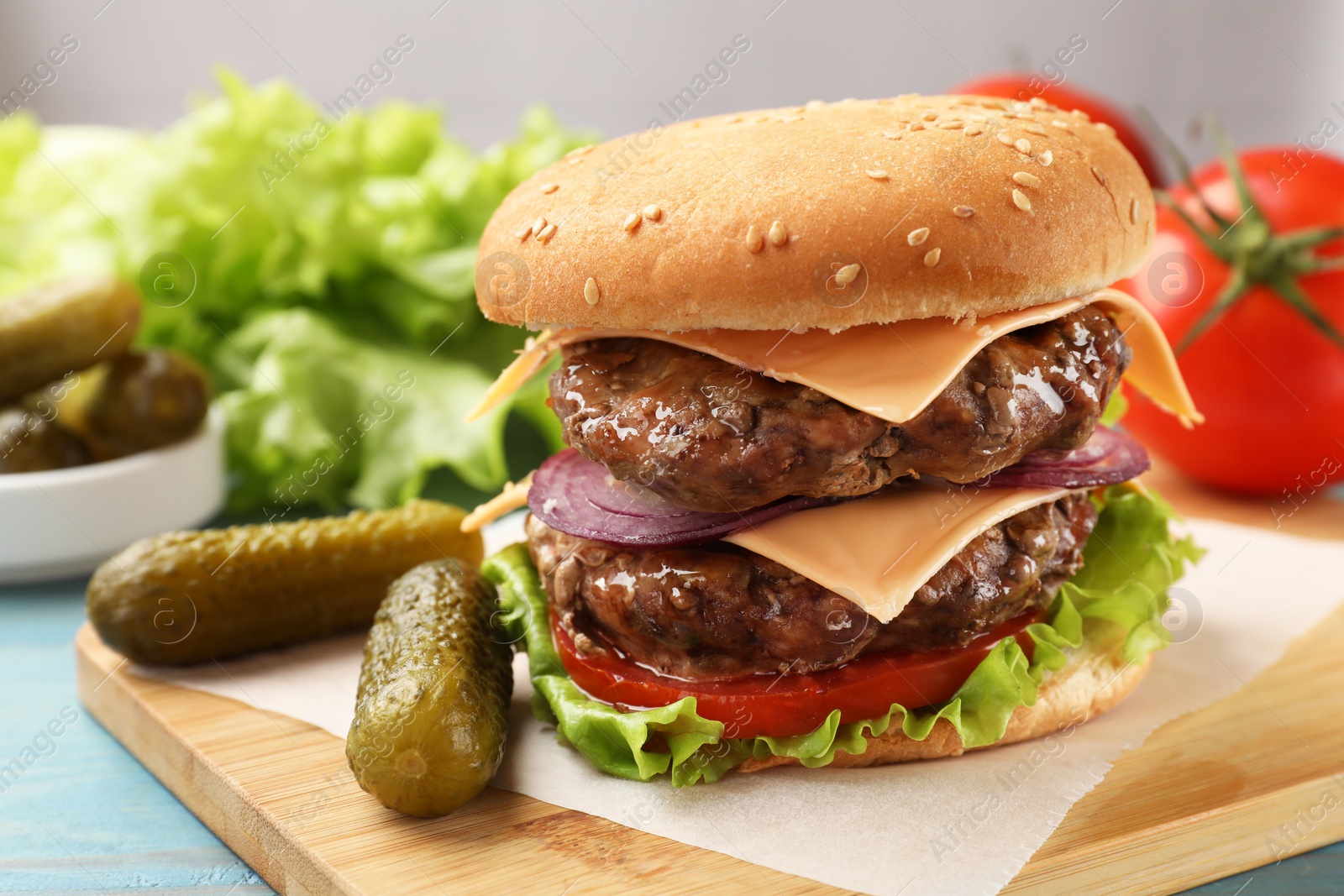 Photo of Tasty hamburger with patties, cheese and vegetables served on table, closeup