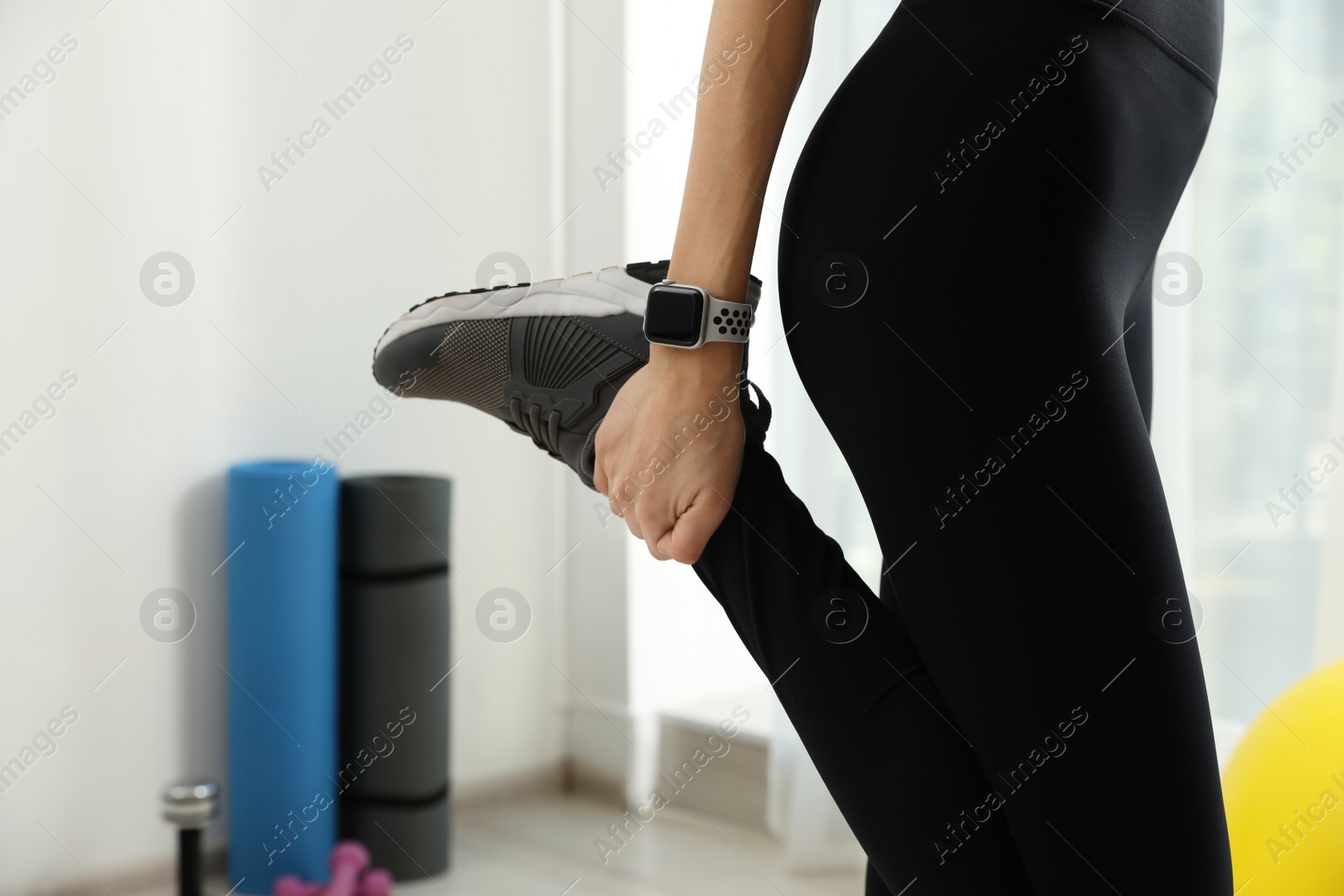 Photo of Young woman wearing smart watch during training indoors, closeup