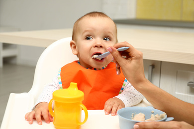 Young mother feeding her little baby at home