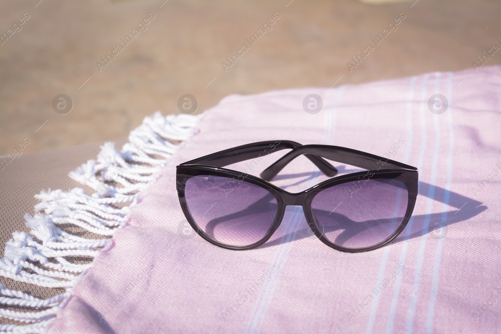 Photo of Stylish sunglasses on blanket outdoors, closeup. Beach accessories