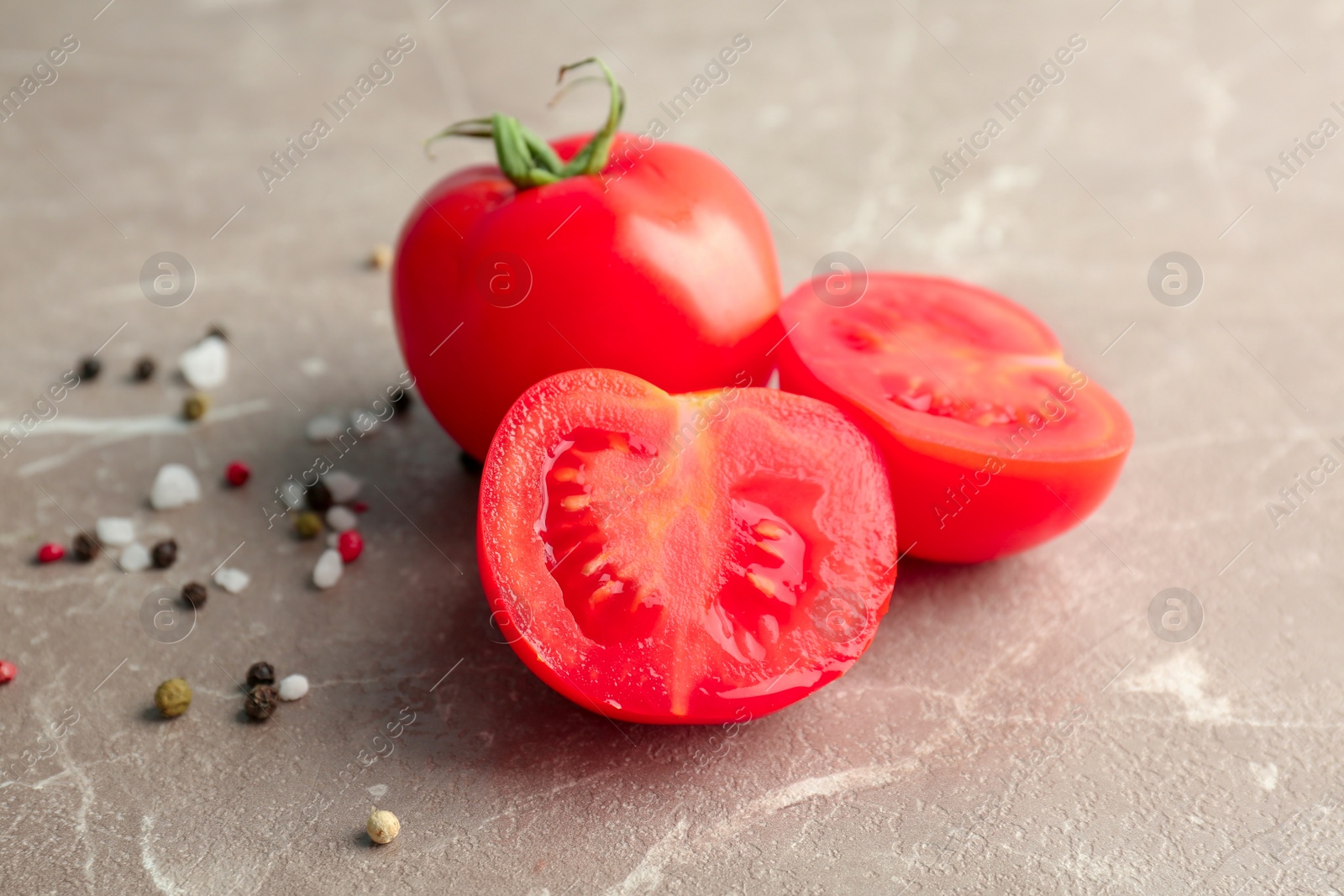 Photo of Fresh ripe tomatoes with salt and pepper on grey background