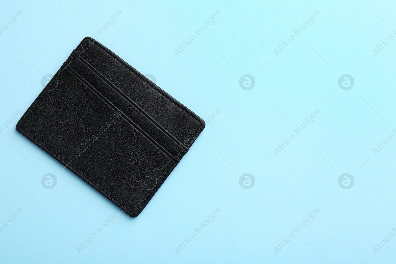 Photo of Empty leather card holder on light blue background, top view. Space for text