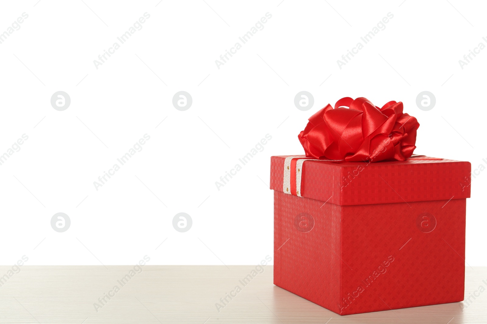 Photo of Red gift box with bow on wooden table against white background, space for text